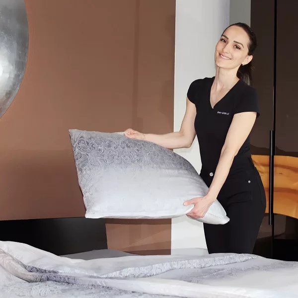 Reinigungsfachkraft von Ever-Clean in Zürich macht das Bett für den Home Hotel Service mit einer Kissenunterlage.