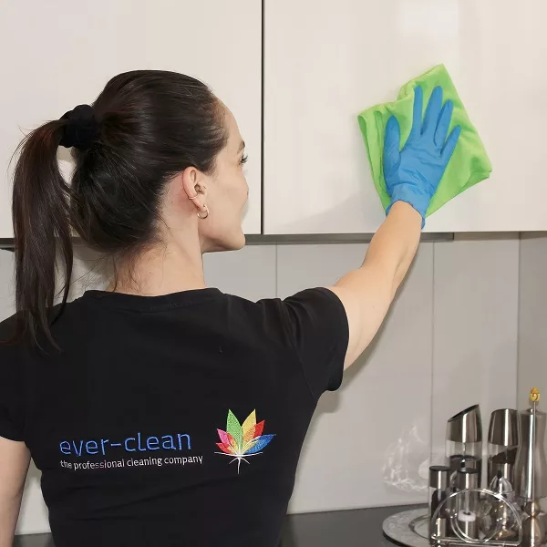 Reinigungsfachkraft von Ever-Clean in Zürich reinigt Küchenmöbel mit einem Mikrofasertuch.